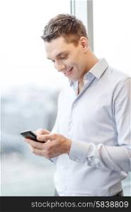business, technology, internet and office concept - smiling businessman with smartphone in office