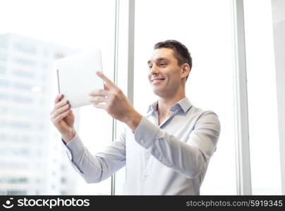 business, technology, internet and office concept - smiling businessman with tablet pc computer in office