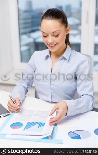 business, technology, internet and office concept - smiling businesswoman with laptop and charts in office