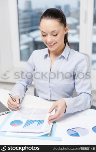 business, technology, internet and office concept - smiling businesswoman with laptop and charts in office