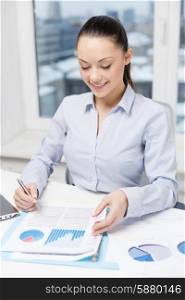 business, technology, internet and office concept - smiling businesswoman with laptop and charts in office