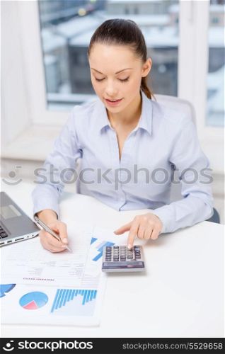 business, technology, internet and office concept - smiling businesswoman with laptop, calculator and charts in office