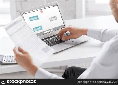 business, technology, internet, online communication and people concept - close up of businessman with messenger on laptop computer screen working at office