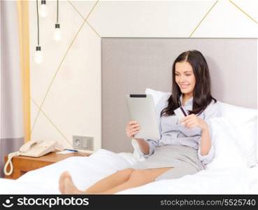 business, technology, internet, online shopping and hotel concept - happy businesswoman with tablet pc computer and credit card lying in bed