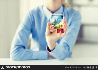 business, technology, mass media and people concept - close up of woman hand holding and showing showing news application on transparent smartphone screen at office
