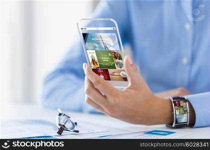 business, technology, mass media, internet and people concept - close up of woman hand holding and showing showing news application on transparent smartphone screen at office