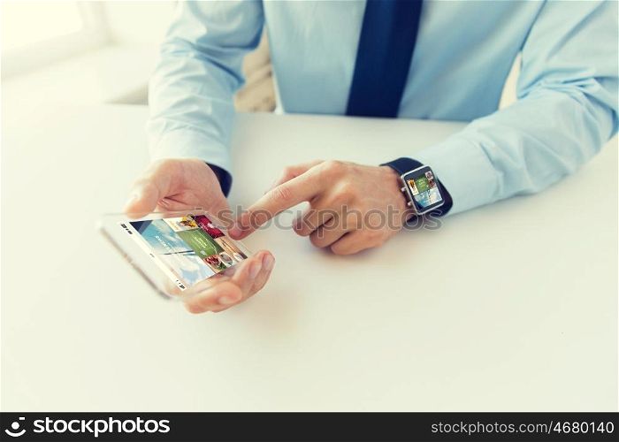 business, technology, media and people concept - close up of male hand holding and showing transparent smart phone and watch at office with web applications on screen
