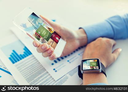 business, technology, media and people concept - close up of woman hand holding transparent smartphone and wearing smartwatch with news application