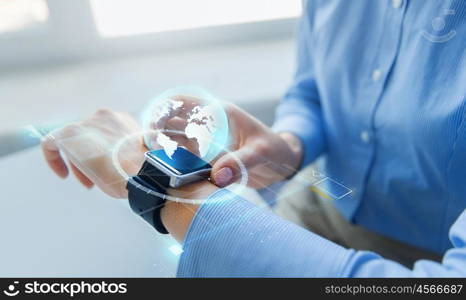 business, technology, network, communication and people concept - close up of woman hands setting smart watch with earth globe hologram at office