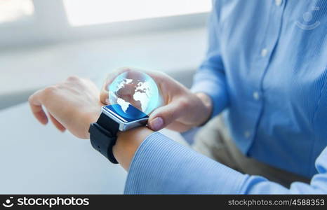 business, technology, network, communication and people concept - close up of woman hands setting smart watch with earth globe hologram at office