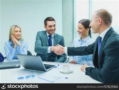 business, technology, partnership and people concept - two smiling businessman shaking hands in office
