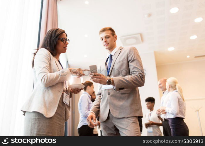 business, technology, people and education concept - happy couple with smartphone at international conference. couple with smartphone at business conference