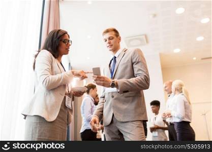 business, technology, people and education concept - happy couple with smartphone at international conference. couple with smartphone at business conference