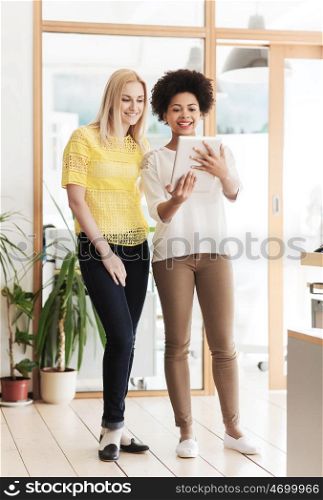 business, technology, people and teamwork concept - happy creative team of two women with tablet pc computer in office