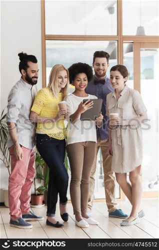 business, technology, people and teamwork concept - happy international creative team of two women and man with tablet pc computer and coffee in office