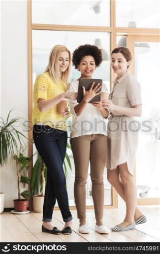 business, technology, people and teamwork concept - happy international creative team of three women with tablet pc computer and coffee in office