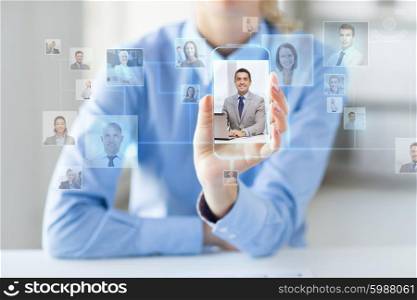 business, technology, social network, head hunting and people concept - close up of woman hand holding and showing transparent smartphone with contact icons on screen at office