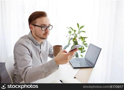 business, technology, startup and people concept - businessman or creative male worker texting on smarphone and drinking coffee at home office