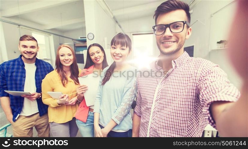 business, technology, startup and people concept - happy international creative business team taking selfie at office. creative business team taking selfie at office