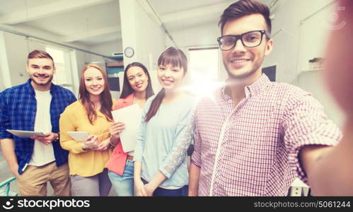 business, technology, startup and people concept - happy international creative business team taking selfie at office. creative business team taking selfie at office