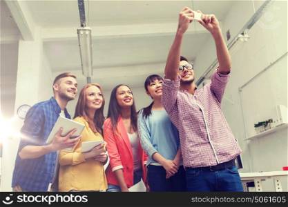 business, technology, startup and people concept - happy international creative business team taking selfie at office. creative business team taking selfie at office
