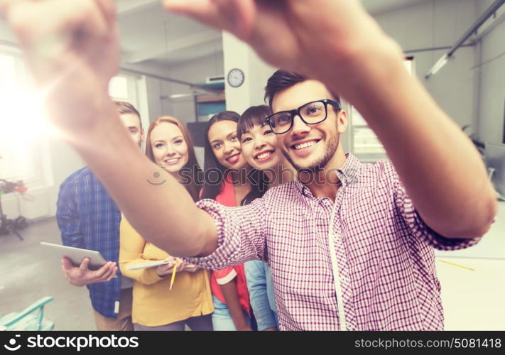 business, technology, startup and people concept - happy international creative business team taking selfie at office. creative business team taking selfie at office