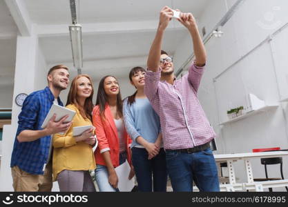 business, technology, startup and people concept - happy international creative business team taking selfie at office