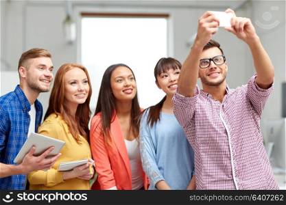business, technology, startup and people concept - happy international creative team taking selfie at office. creative business team taking selfie at office