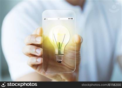 business, technology, startup, idea and people concept - close up of male hand holding and showing transparent smartphone with light bulb icon