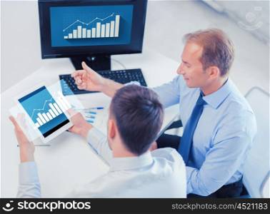 business, technology, statistics, economics and people concept - businessmen with charts on tablet pc and computer at office