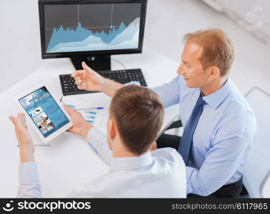 business, technology, statistics, economics and people concept - businessmen with charts on tablet pc and computer at office