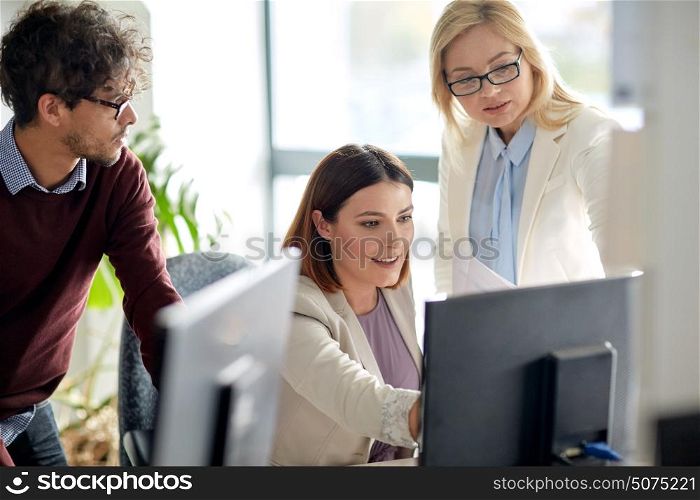 business, technology, teamwork and people concept - happy creative team with computer in office. happy business team with computer in office