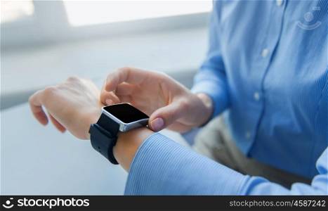 business, technology, time and people concept - close up of woman hands setting smart watch at office