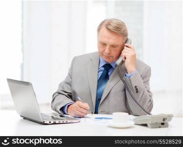 business, technologym communication and office concept - busy older businessman with laptop, charts, coffee and telephone in office