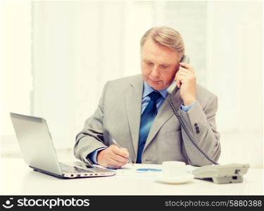 business, technologym communication and office concept - busy older businessman with laptop, charts, coffee and telephone in office