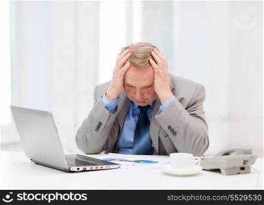 business, technologym communication and office concept - upset older businessman with laptop, charts, coffee and telephone in office
