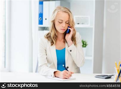 business, tecnology, communication and people concept - businesswoman with pen and notebook calling on smartphone at office