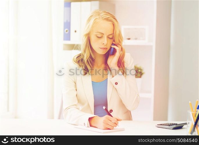 business, tecnology, communication and people concept - businesswoman with pen and notebook calling on smartphone at office. businesswoman calling on smartphone at office. businesswoman calling on smartphone at office