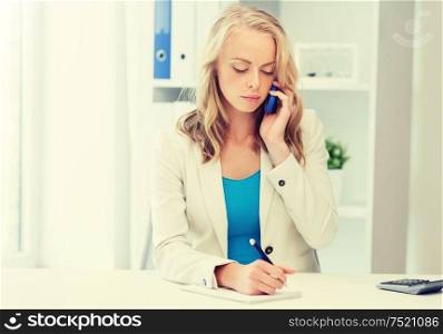 business, tecnology, communication and people concept - businesswoman with pen and notebook calling on smartphone at office. businesswoman calling on smartphone at office