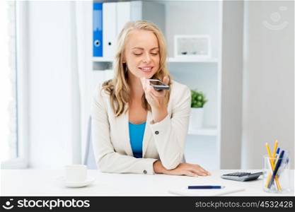 business, tecnology, communication and people concept - happy businesswoman drinking coffee and using voice command or recorder on smartphone at office