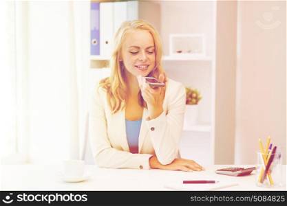 business, tecnology, communication and people concept - happy businesswoman drinking coffee and using voice command or recorder on smartphone at office. businesswoman using voice command on smartphone. businesswoman using voice command on smartphone