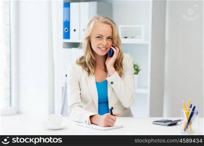 business, tecnology, communication and people concept - happy businesswoman with pen and notebook calling on smartphone at office
