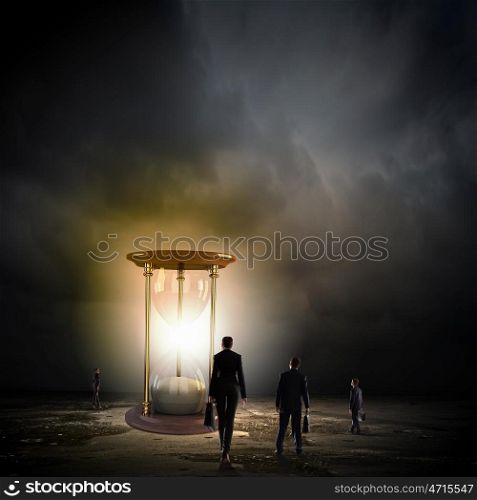 Business time. Conceptual image of business people looking at sandglass