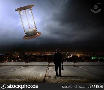 Business time. Conceptual image with sandglass and rear view of businessman
