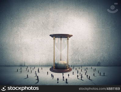 Business time. Conceptual image with sandglass and silhouettes of business people around