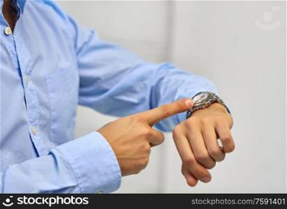 business, time management and people concept - close up of businessman looking at wristwatch on his hand. close up of businessman looking at wristwatch