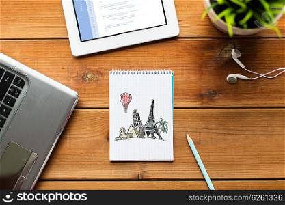 business, tourism, business and technology concept - close up of notebook with landmarks drawing, laptop and tablet pc computer on wooden table