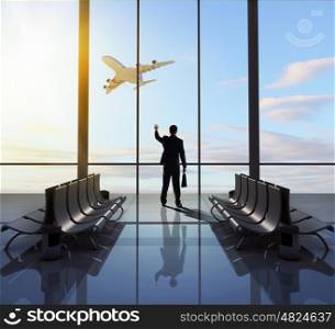 Business travel. Businessman at airport looking at airplane taking off