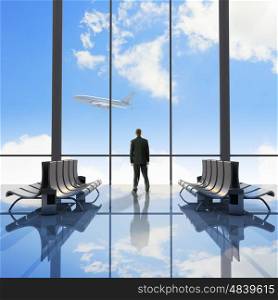 Business travel. Businessman at airport looking at airplane taking off