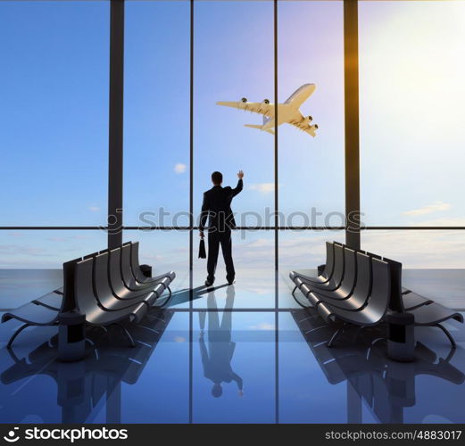 Business travel. Businessman at airport looking at airplane taking off